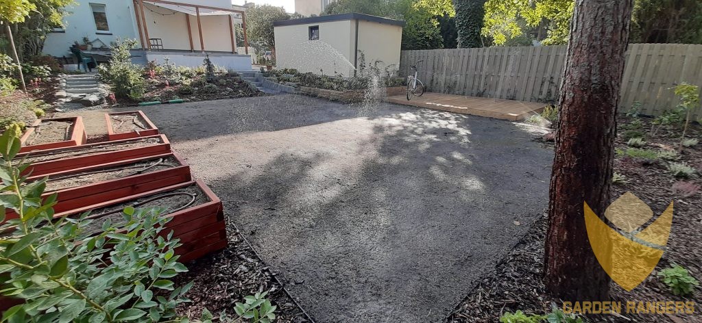 Świeżo wysiana trawa podlewana przez automatyczny system podlewania. Donice w użytkowym ogrodzie warzywnym są automatycznie nawadniane przez system kropelkowy.