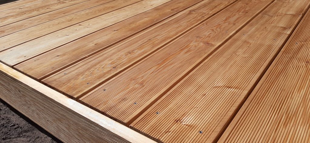 Elegancko wykończony taras drewniany z modrzewia syberyjskiego, przymocowany do legarów za pomocą nierdzewnych wkrętów firmy SPAX w technologii zagłębiania łebków śrub.